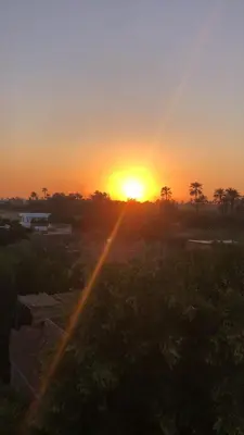 a sunset with the sun setting in a city at Roses House Ladies or families only in Luxor
