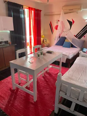 a room with two beds and a white table and a bed at Roses House Ladies or families only in Luxor