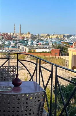 a table and chair on a balcony with a view of a city at One bedroom with sea view in the centre in Hurghada