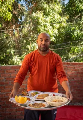 a man holding a tray of food on a table at Kashta Nubian Guest Houst in Aswan
