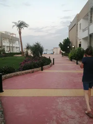 a woman walking down a sidewalk near the beach at Cecelia Resort Hurghada in Hurghada