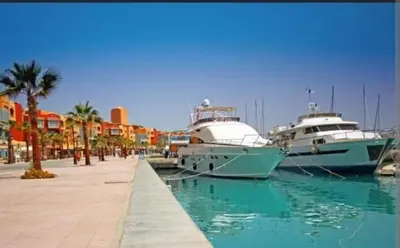 two boats docked in a marina with palm trees and buildings at Sheraton Plaza Marina Blast 2 bedroom 2 bathroom in Hurghada