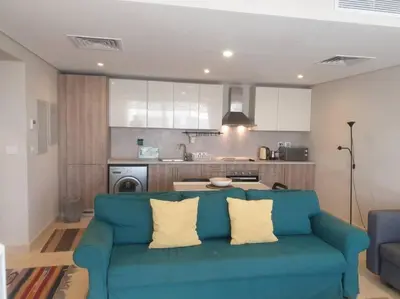 a living room with a blue couch and a kitchen at Mangroovy - Divine 1BR Hotel view in Hurghada