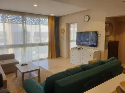 a living room with a green couch and a television at Mangroovy - Divine 1BR Hotel view in Hurghada