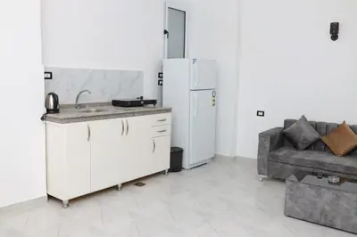 a kitchen with a sink and a refrigerator and a couch at Diamond Guest House in Luxor