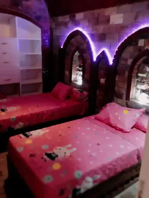 two beds in a room with purple lights at Shahhat Flat in Luxor