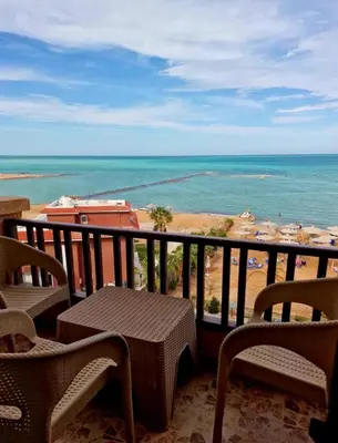 a balcony with a table and chairs and the ocean at Hurghada Concierge at Turtles Beach Resort in Hurghada