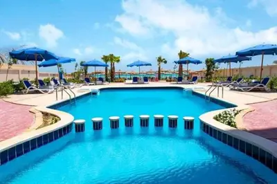 a large swimming pool with blue umbrellas and chairs at Casablanca beach family suites in Hurghada