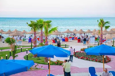a group of people walking on the beach with umbrellas at Casablanca beach family suites in Hurghada