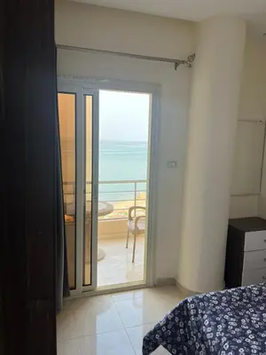 a bedroom with a door open to a balcony with the ocean at Casablanca beach family suites in Hurghada