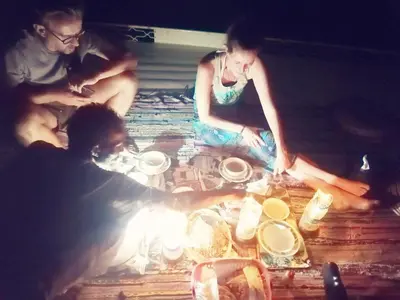 a group of people sitting on the floor with a fire at Aswan Felucca sailing boat and Hotel in Aswan