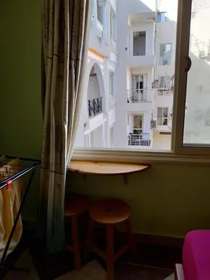 a table and two stools in front of a window at شقة 327صغيرة جميلة هادئة وسط المدينة in Hurghada