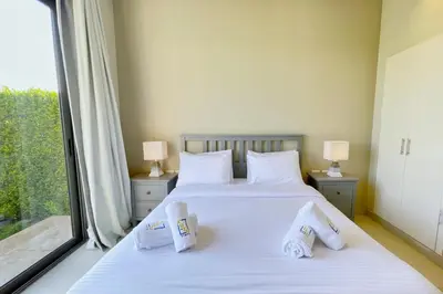 a bedroom with a bed with white sheets and a window at Homey 3 BDR Townhouse Tawila El Gouna in Hurghada