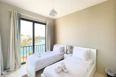two beds in a room with a large window at Homey 3 BDR Townhouse Tawila El Gouna in Hurghada