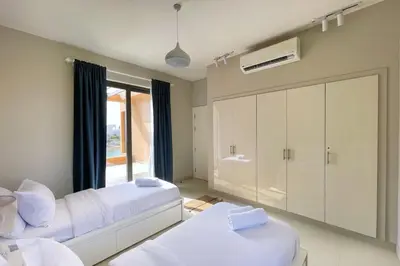 a bedroom with two beds and a large window at Homey 3 BDR Townhouse Tawila El Gouna in Hurghada