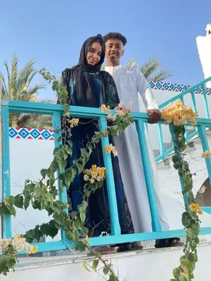 a man and a woman standing on a blue railing at Miskaa Nubian House in Naj‘ Tinjār