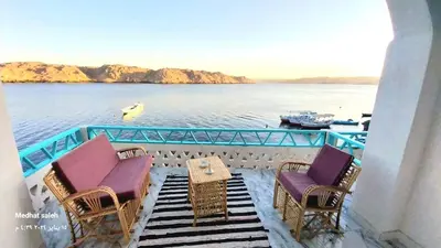 a balcony with chairs and a table and water at Miskaa Nubian House in Naj‘ Tinjār