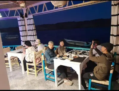a group of people sitting at tables in a restaurant at Miskaa Nubian House in Naj‘ Tinjār