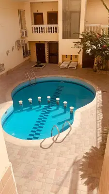 a large swimming pool in a courtyard with a building at hurghada home in Safaga
