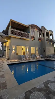a house with a swimming pool in front of a house at Yasmine Guest House in Luxor