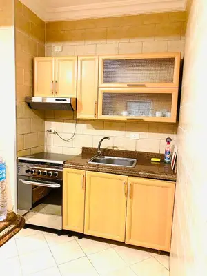 a kitchen with wooden cabinets and a sink at Apartment Sahl Hasheesh 1+1 in Hurghada