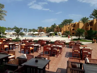 an outdoor patio with tables and chairs and a pool at sahl hashesh makadi- hurghada- in Hurghada