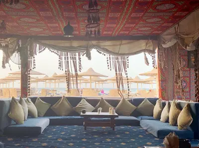 a living room with a blue couch in front of a beach at sahl hashesh makadi- hurghada- in Hurghada