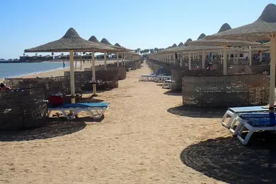 a beach with umbrellas and chairs on the sand at sahl hashesh makadi- hurghada- in Hurghada