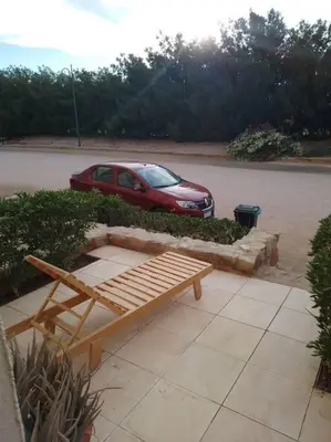 a red car parked in a parking lot with a bench at Mountain view apartment in Makadi Heights in Hurghada