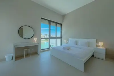 a white bedroom with a large bed and a mirror at 4BR Villa with Private Pool Tawila Lagoon El Gouna in Hurghada