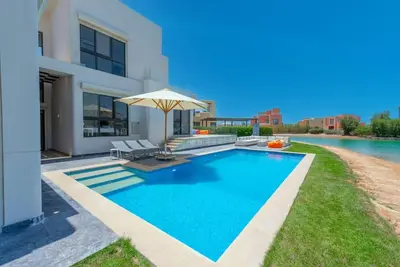 a swimming pool with an umbrella next to a house at 4BR Villa with Private Pool Tawila Lagoon El Gouna in Hurghada