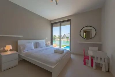 a white bedroom with a bed and a mirror at 4BR Villa with Private Pool Tawila Lagoon El Gouna in Hurghada