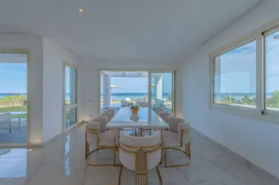 a dining room with a table and chairs and windows at Royal Villa on the beach in Hurghada