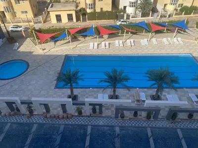 a large swimming pool with palm trees next to a building at Fanadir bay in Hurghada