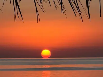 a sunset over the ocean with the sun in the horizon at Das Haus am Meer in Safaga