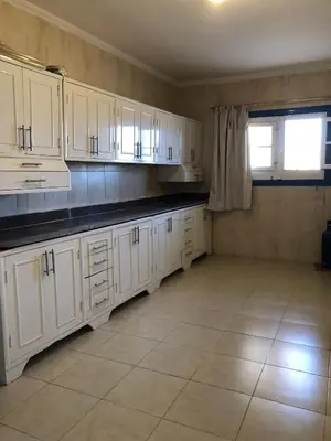 a kitchen with white cabinets and a tile floor at Das Haus am Meer in Safaga