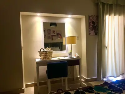a room with a table with a mirror and a chair at Azzura appartment sahl hashesh with private garden in Hurghada