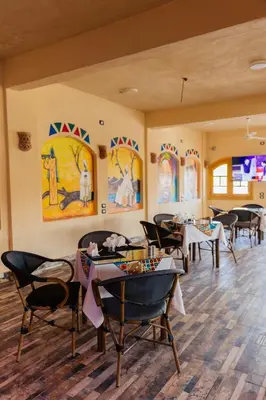 a restaurant with tables and chairs and paintings on the walls at ACHERTOD Nubian House in Naj‘ al Maḩaţţah