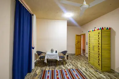 a room with a table and chairs and a blue curtain at ACHERTOD Nubian House in Naj‘ al Maḩaţţah