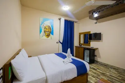 a bedroom with a bed and a painting of a man at ACHERTOD Nubian House in Naj‘ al Maḩaţţah