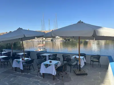 a restaurant with tables and umbrellas next to the water at ACHERTOD Nubian House in Naj‘ al Maḩaţţah