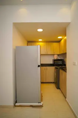 a white refrigerator in a kitchen with wooden cabinets at كمباوند فلورنزا خمسين in Hurghada