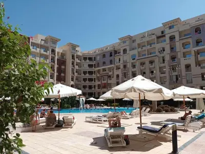 a hotel with a pool and chairs and umbrellas at كمباوند فلورنزا خمسين in Hurghada
