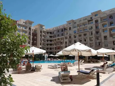 a pool with chairs and umbrellas in front of a large building at كمباوند فلورنزا خمسين in Hurghada