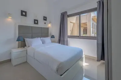 a white bedroom with a white bed and a window at Gcribs apartment pool view in El Gouna