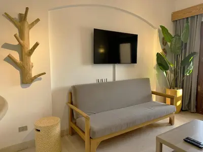 a living room with a couch and a tv on a wall at Artsy 1 BR Apt/ Free Pool & Lagoon Access @ElGouna in Hurghada
