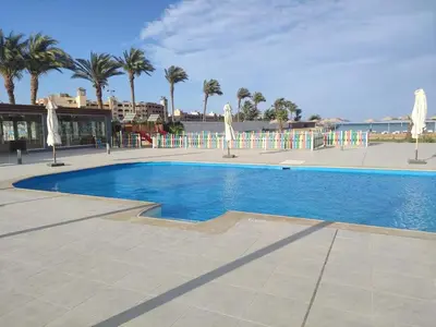 a swimming pool with umbrellas and palm trees at Scandic beach resort in Hurghada