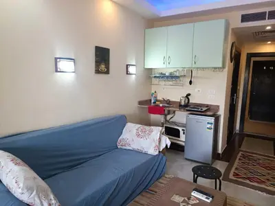 a living room with a blue couch and a kitchen at Harmony Sunny Chalet With Wi-Fi in Hurghada