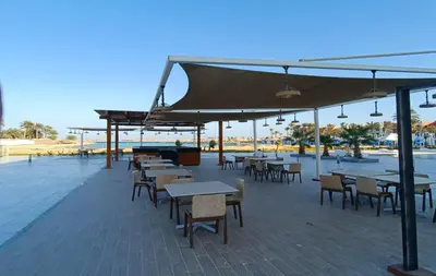 an outdoor patio with tables and chairs and umbrellas at Perfect For couples Sunny & SeaView with Wi-Fi in Hurghada
