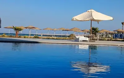 a pool with an umbrella and chairs and umbrellas at Perfect For couples Sunny & SeaView with Wi-Fi in Hurghada